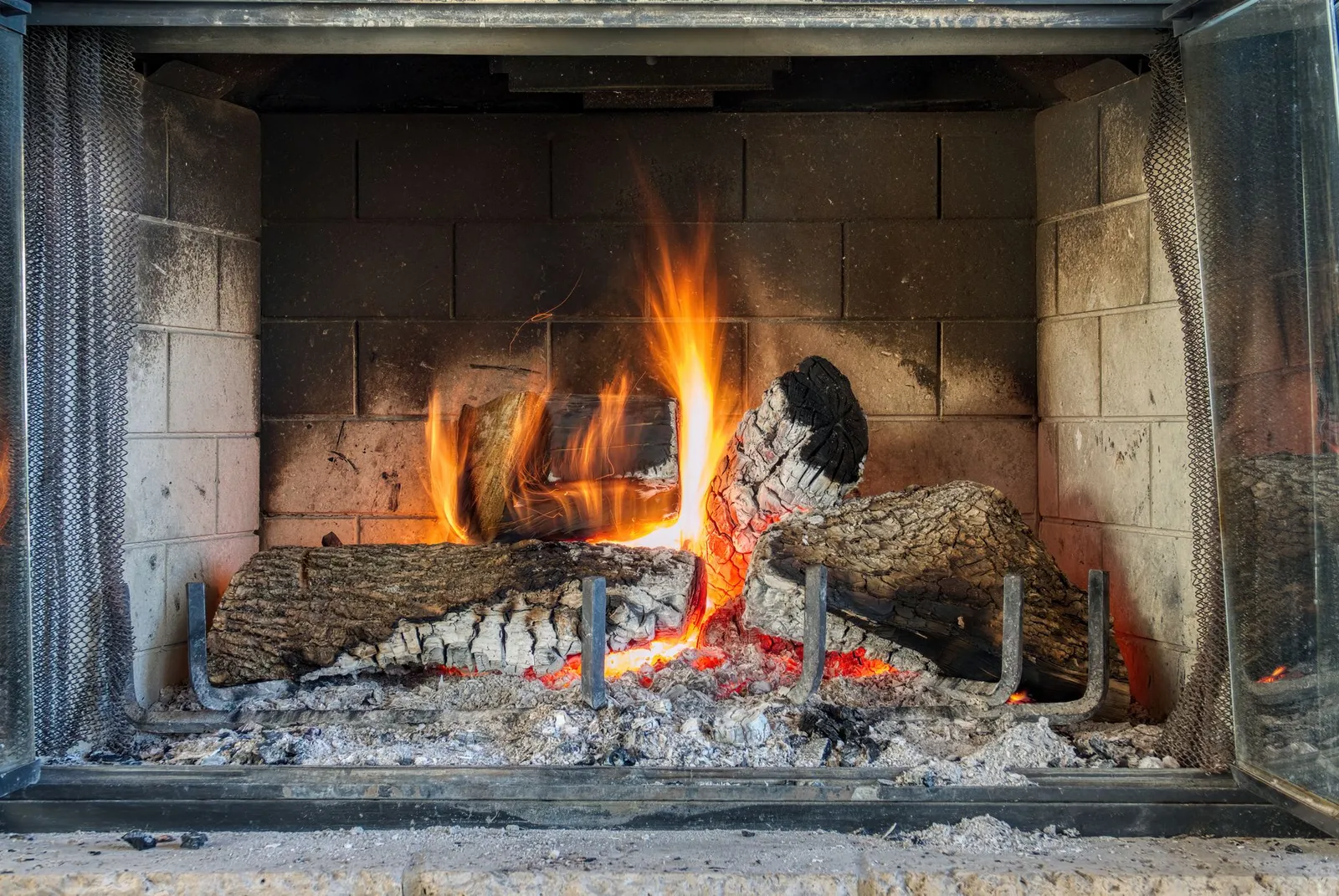 Feu de bûches dans une cheminée à foyer ouvert garnie de briques réfractaires