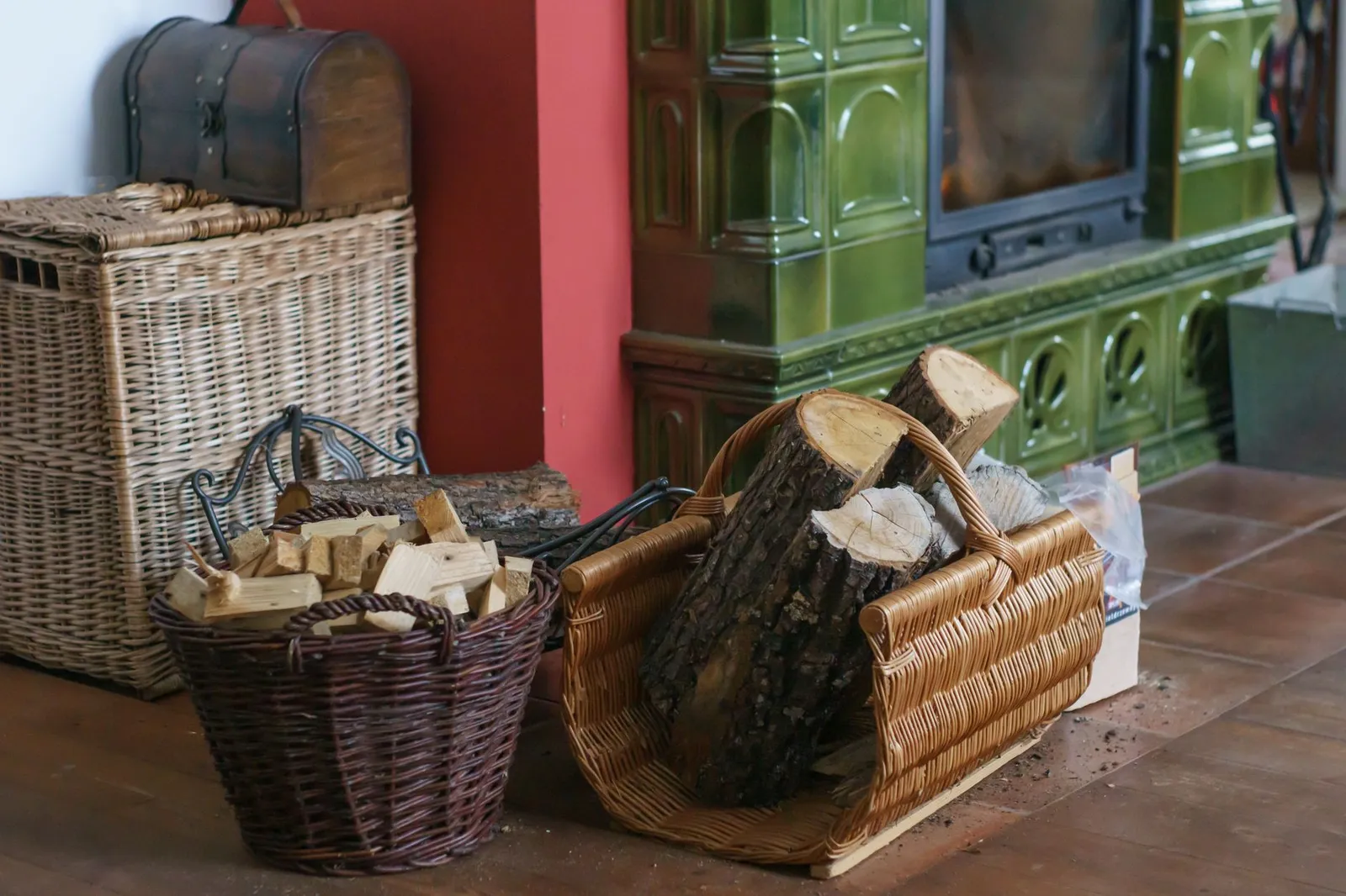 Paniers de bûches et de petit bois posés devant un poêle en faïence